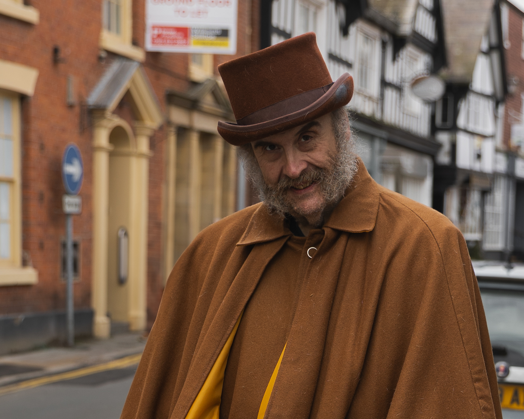 A portrait of a well distinguished gentleman wearing a top hat and matching brown clothes.